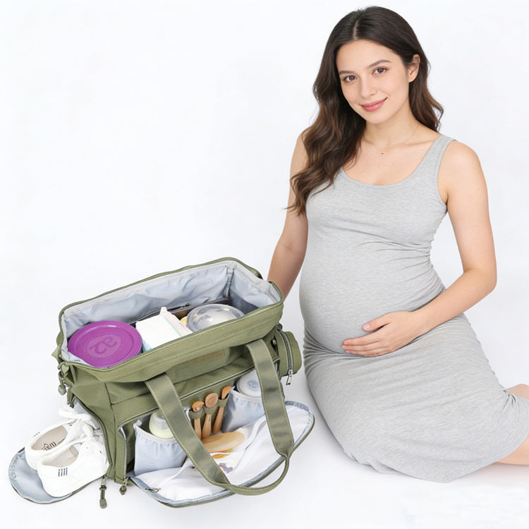 olive green diaper bag tote opened beside an expectant mother showing baby clothes bottle holders and organized storage