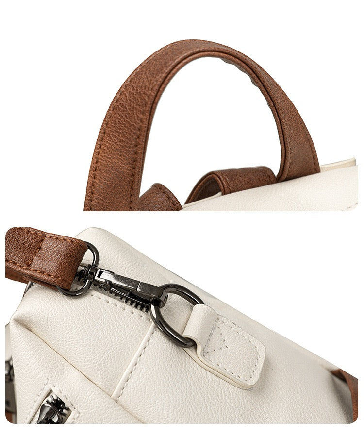 close up of brown top carry handle and detachable metal swivel hook on white pu backpack