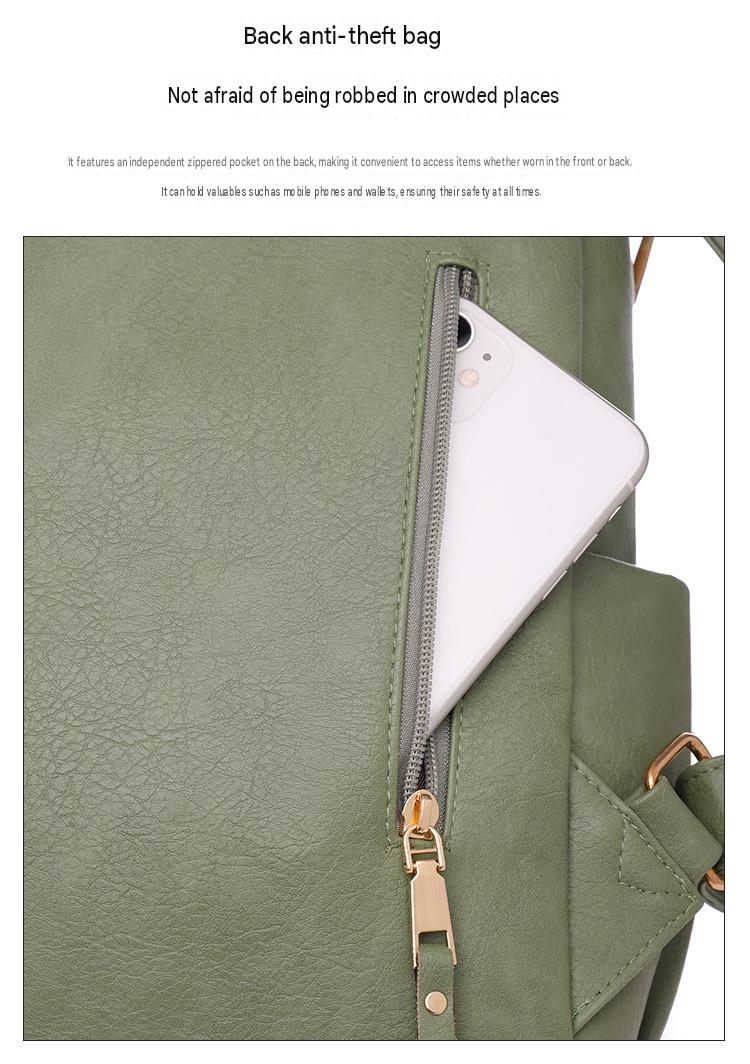 rear zippered pocket on green pu womens backpack shown holding a white mobile phone