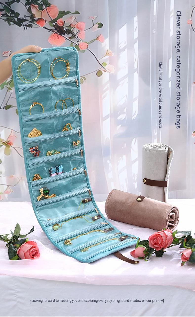 light blue travel jewelry organizer displayed vertically with clear pockets for earrings bracelets and necklaces