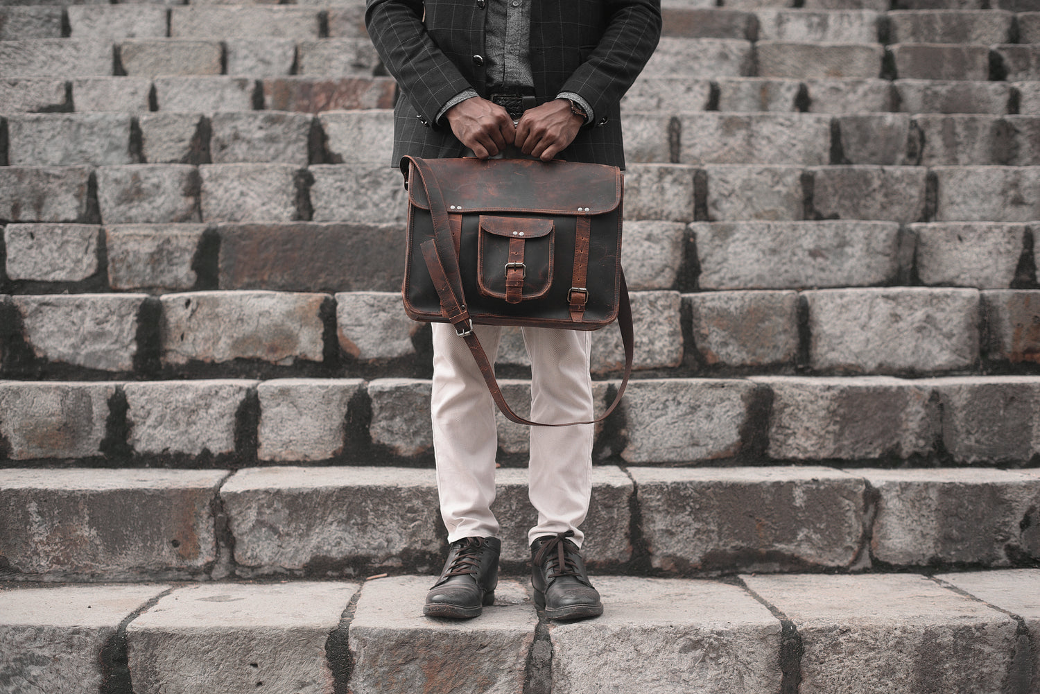 man holding a fanlosn leather bag on a set of stairs