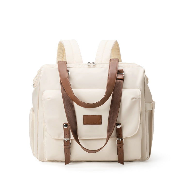 off-white convertible diaper bag tote backpack with brown shoulder straps front flap pocket side storage and top zipper