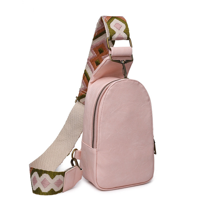 pink custom pu sling bag with rounded zippered body adjustable geometric woven shoulder strap and metal hardware