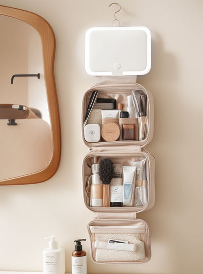 top view of three section makeup bag with open mirror brush holders clear storage pockets and cosmetics